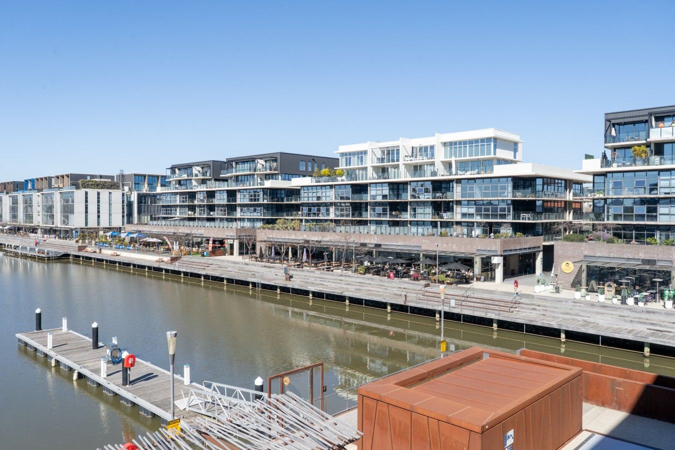 A waterfront building with multiple floors, outdoor seating, and a dock.