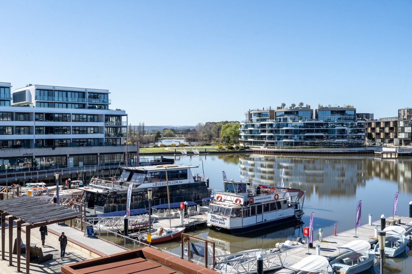 A marina with boats docked, a modern building with multiple floors, and a clear sky.