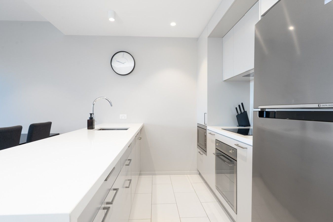 Una cocina moderna con una isla central, electrodomésticos de acero inoxidable y un reloj de pared.