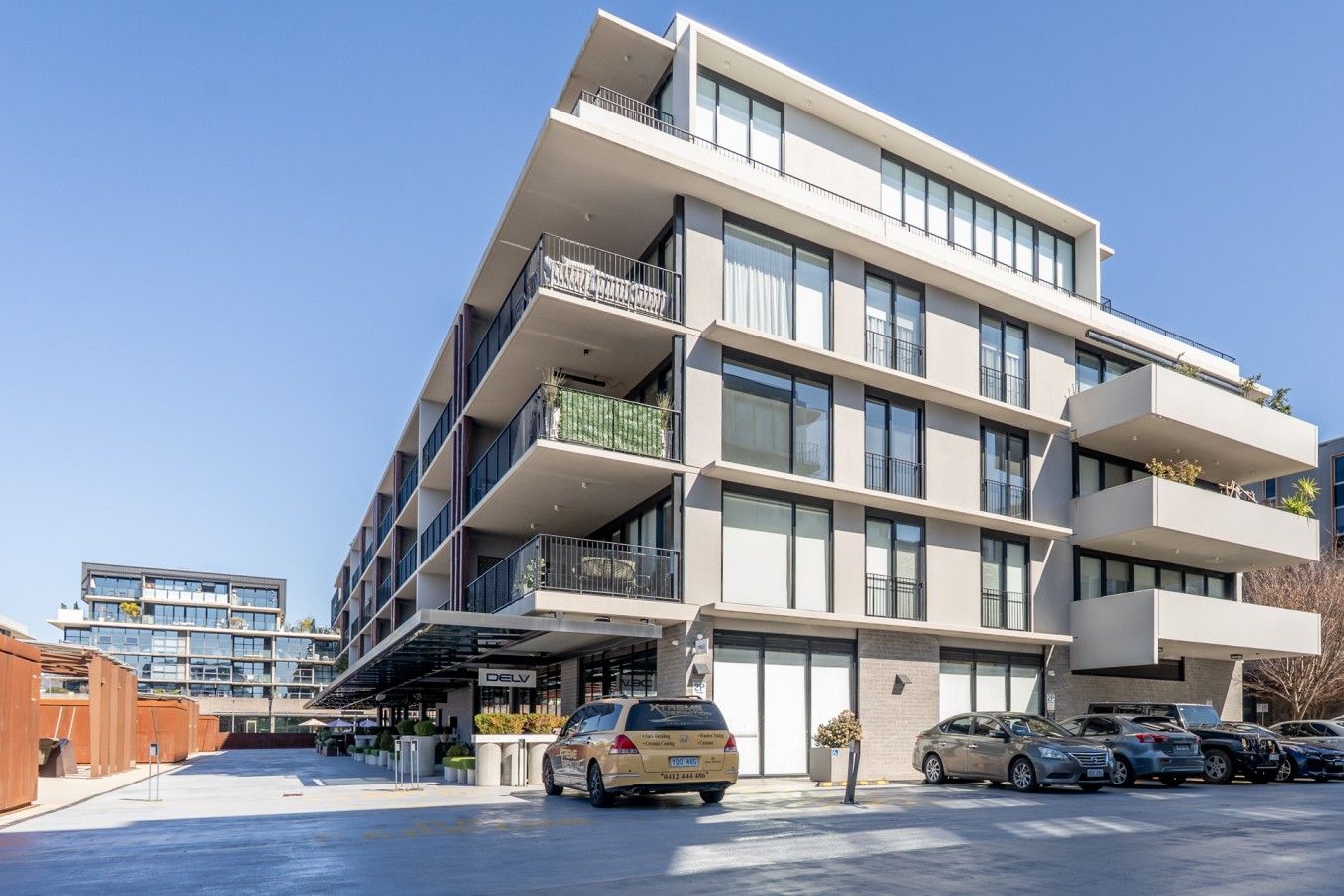 Ein mehrstöckiges Gebäude mit modernem Design, mit Balkonen und großen Fenstern.