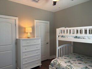 A bedroom with a bunk bed, a dresser with drawers, a lamp, and a door. - New listing!  Open Labor Day! Pools, Beach, Pickleball! (Gulf Shores)