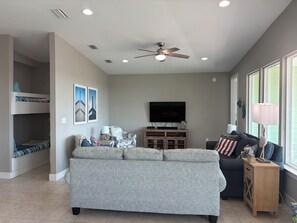 A living room with a sofa, a television, a ceiling fan, and a window. - New listing!  Open Labor Day! Pools, Beach, Pickleball! (Gulf Shores)