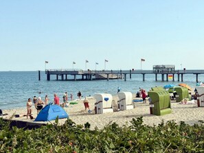 A beach with portable tents and a pier extending into the water. - Holiday Apartment With 1 Bedroom (Wyk auf Foehr)