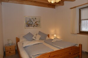 Ein Schlafzimmer mit einem hölzernen Bett, zwei Nachttischen, einer Nachttischlampe und einem Fenster mit Vorhängen.