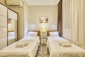 A hotel room with two beds, a bedside table with a lamp, a wall-mounted air conditioner, and a mirror. - The Blue House, Triplex, Best Location at Taksim (Istanbul)