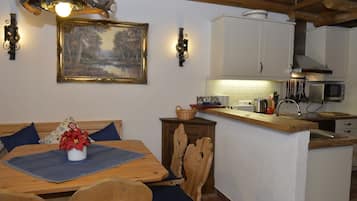 Uma sala de jantar com mesa de madeira, cadeiras e um quadro na parede.