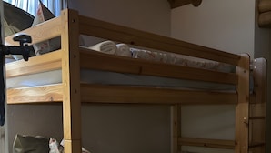 En køjeseng med træramme, madras, puder og en lille opbevaringsskuffe.
