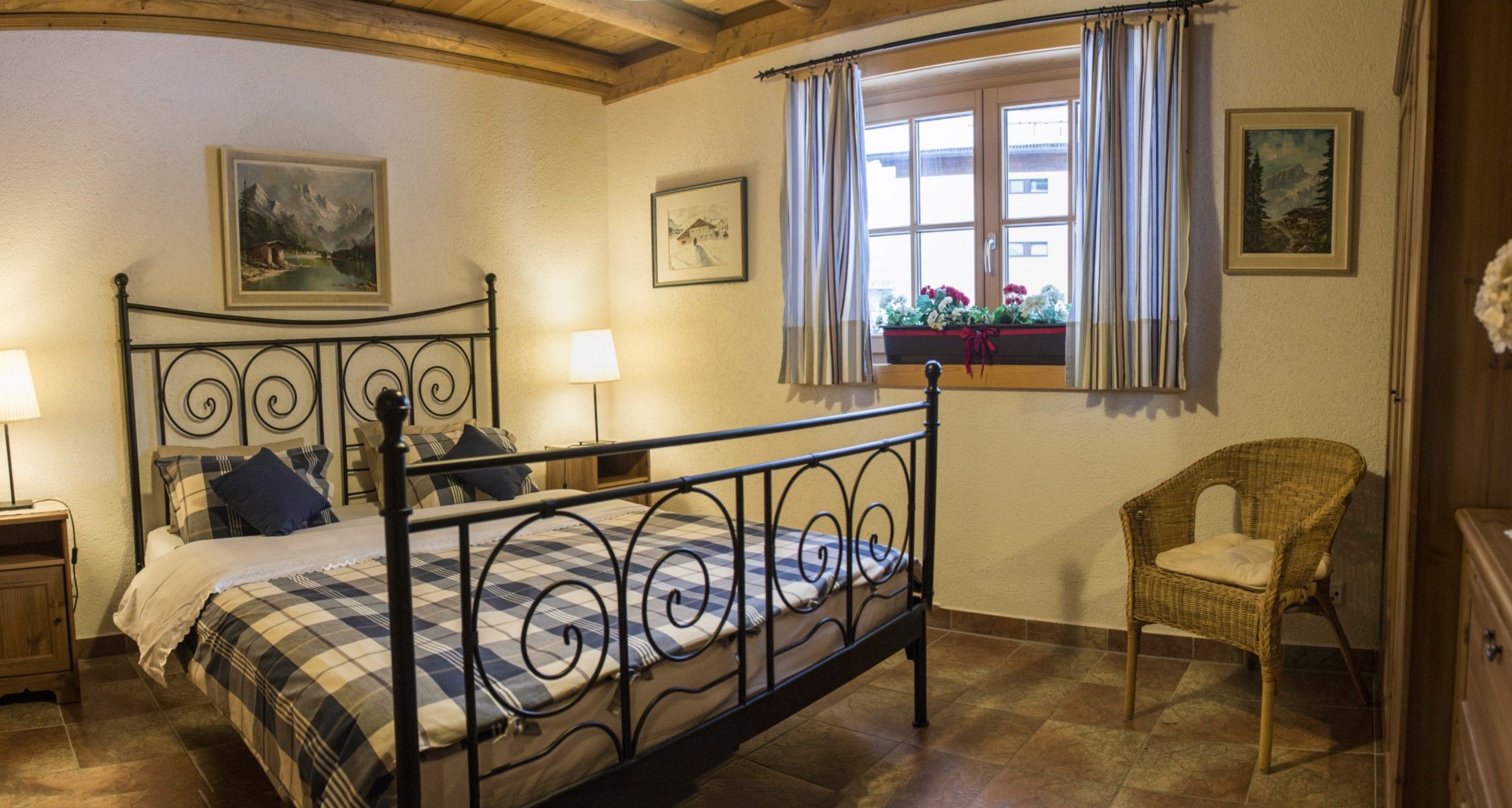 Quarto com cama, duas mesas de cabeceira, janela com cortinas e uma cadeira.