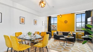 Una sala de estar moderna con comedor, que incluye un sofá, una mesa de centro y una mesa de comedor con sillas.