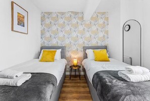 Ein Hotelzimmer mit zwei Betten, einem Nachttisch mit Lampe, einer Wanduhr und einem gerahmten Bild.