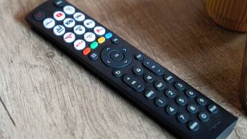 A black remote control with various buttons and symbols, including a numeric keypad and directional arrows.