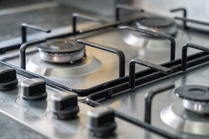 A gas stove with four burners and a control knob. - The Craftsman 3BR Apt, JQ Birmingham with Parking (Birmingham)