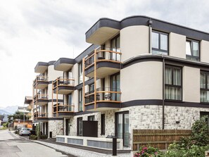Un immeuble résidentiel à plusieurs étages, doté de balcons, d’une façade en pierre et donnant sur la rue.
