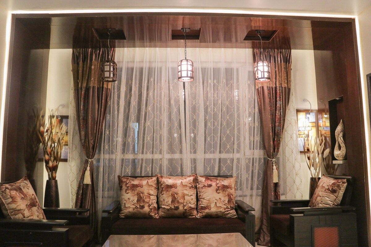 Une chambre avec un lit, une table de chevet, une lampe et une fenêtre avec des rideaux.