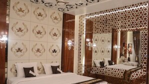 Habitación de hotel con una cama grande, un espejo y papel tapiz estampado.