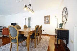 A dining area with a wooden table and chairs, a chandelier, a clock, and a framed picture on the wall. - Elite, Tastefully Furnished, 3BR (Istanbul)