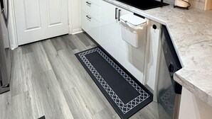 Een kleine keuken met witte kastjes, een zwarte spoelbak en een marmeren achterwand.