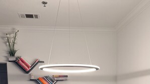 A modern office space with a desk, two monitors, a chair, a black rug, and a unique ceiling light fixture. - Modern Furnished Retreat Cozy & Convenient (Castle Rock)