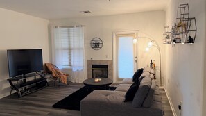 Ein Wohnzimmer mit Flachbildfernseher, Kamin, Sofa und Couchtisch.