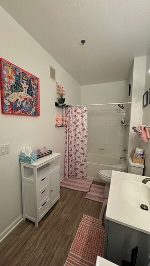 Une salle de bain équipée d’une douche, de toilettes, d’un lavabo et d’un meuble contenant des serviettes.