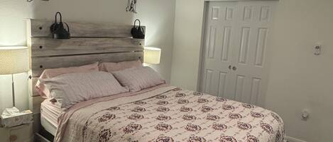 A bedroom with a bed, bedside tables, a ceiling fan, and a door.