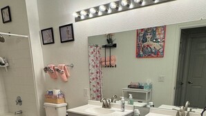 Een badkamer met een wastafelmeubel met dubbele wastafel, toilet, bad en douche.
