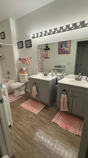 Ein Badezimmer mit doppelter Waschtischablage, Toilette, Badewanne und Dusche.