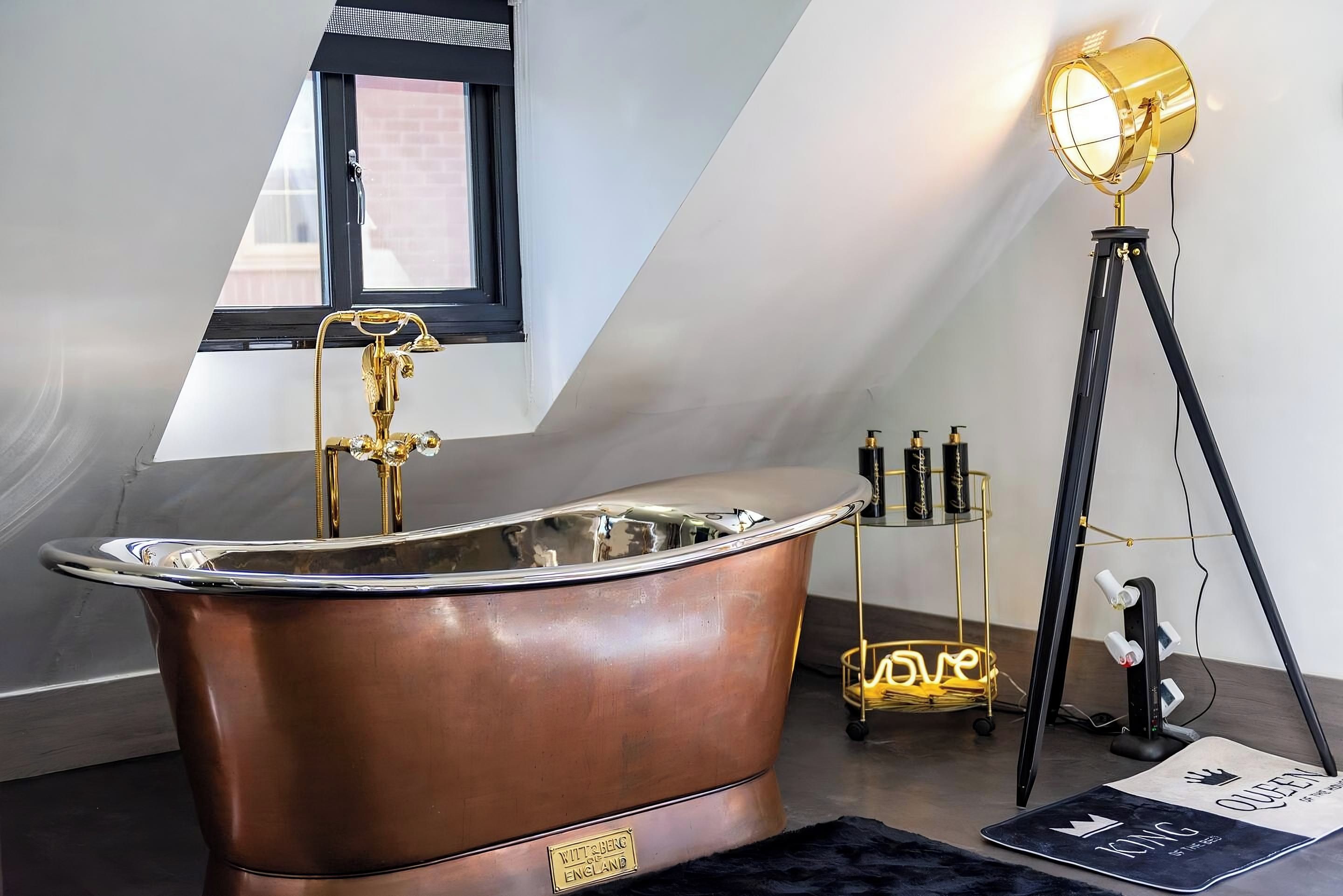 A modern bathroom with a freestanding bathtub, a window with a black frame, and a floor lamp.