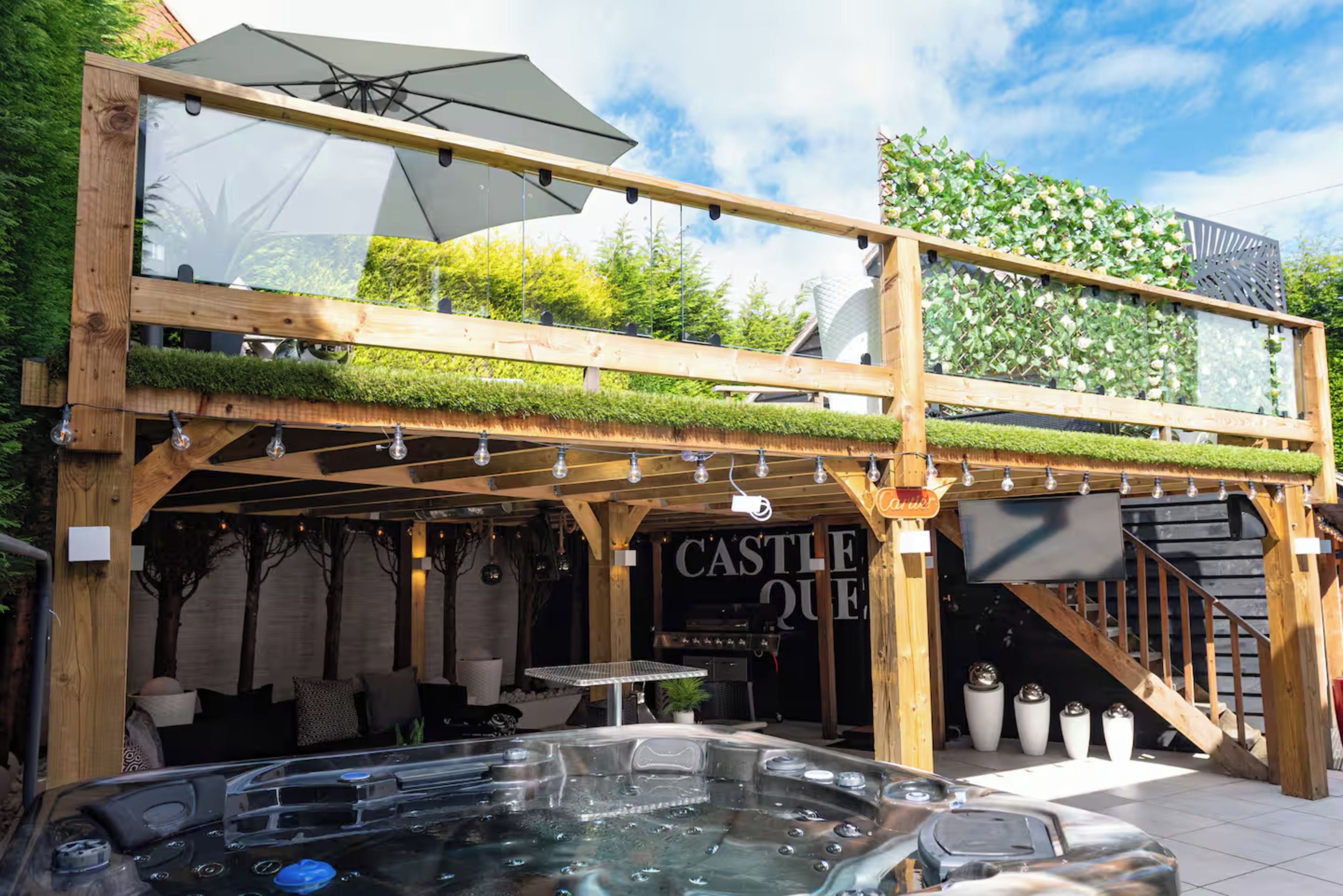 A wooden structure with a hot tub, a sign reading 'CASTLE QUEEN,' and a glass umbrella.
