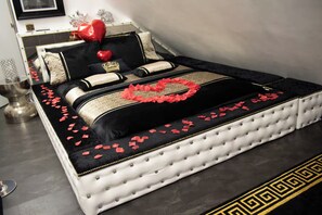 Una cama decorada con un adorno con forma de corazón y pétalos de rosa.