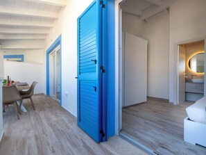 Ein modernes Interieur mit Essbereich, einer blauen Tür und einem Badezimmer mit rundem Spiegel.