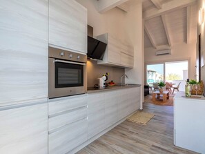Een moderne keuken met een inbouwoven, een flatscreen televisie en een eethoek met een tafel en stoelen.