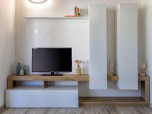 A modern living room with a flat-screen TV, wooden shelves, and a decorative vase. - Nice apartment for 6 guests with A/C, WIFI, TV and patio (Valledoria)