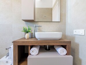 Ein Badezimmer mit einem Holzlagerflächezimmer, einem weißen Waschbecken und einem Spiegel darüber.