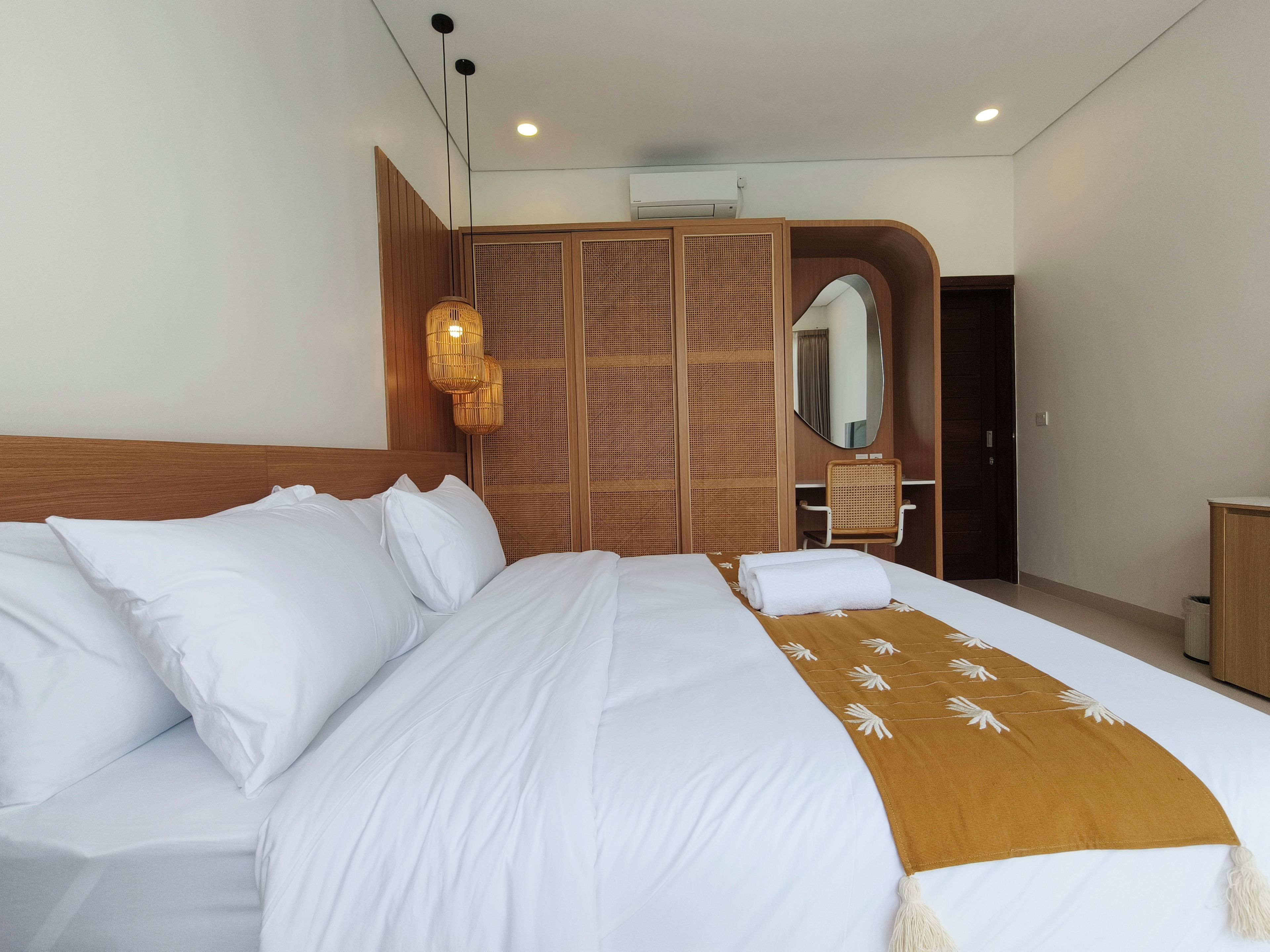 Una habitación de hotel con una cama grande, un armario de madera, un escritorio y un espejo.