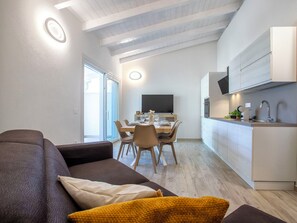 Ein zeitgemäßer Wohnraum mit Essbereich, Küche und einem großen Fenster für natürliches Licht.