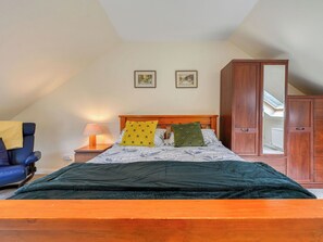 Ein Schlafzimmer mit einem Bett, einem Nachttisch, einer Lampe, einem Sessel und einem Kleiderschrank.