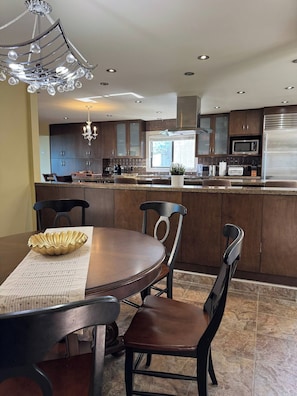 A modern kitchen with dark wood cabinets, a stainless steel refrigerator, and a central island with seating.
