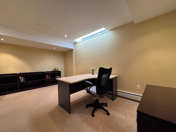 A room with a desk, chair, bookshelf, and a ceiling light fixture.