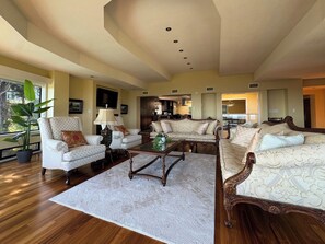 A spacious living room with a large sofa, armchairs, a coffee table, and a potted plant.
