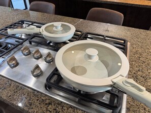 A kitchen with a gas stove, pots, and a range hood.