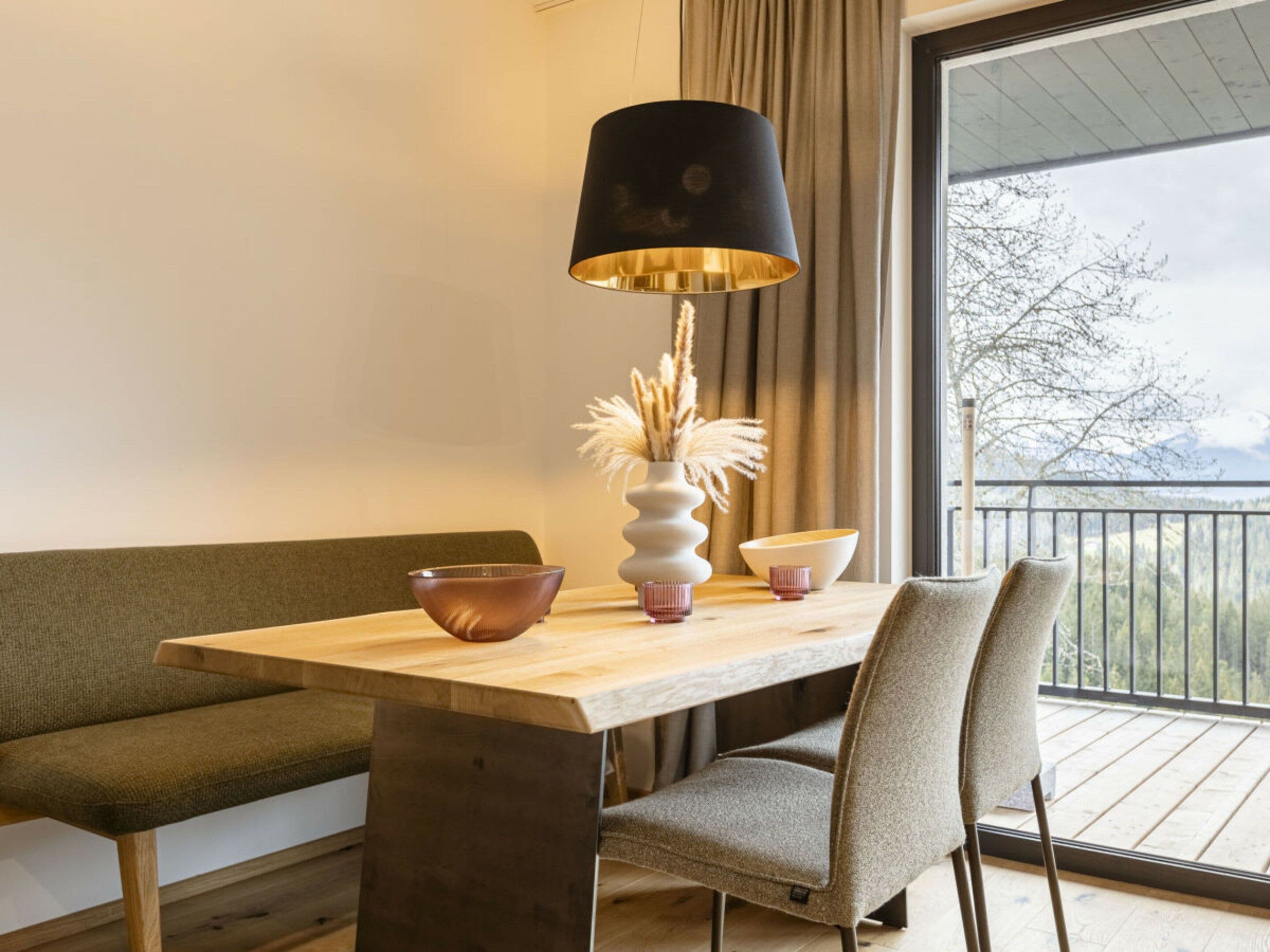Et moderne spiseområde med et træbord, en sort lampe og udsigt til en balkon.