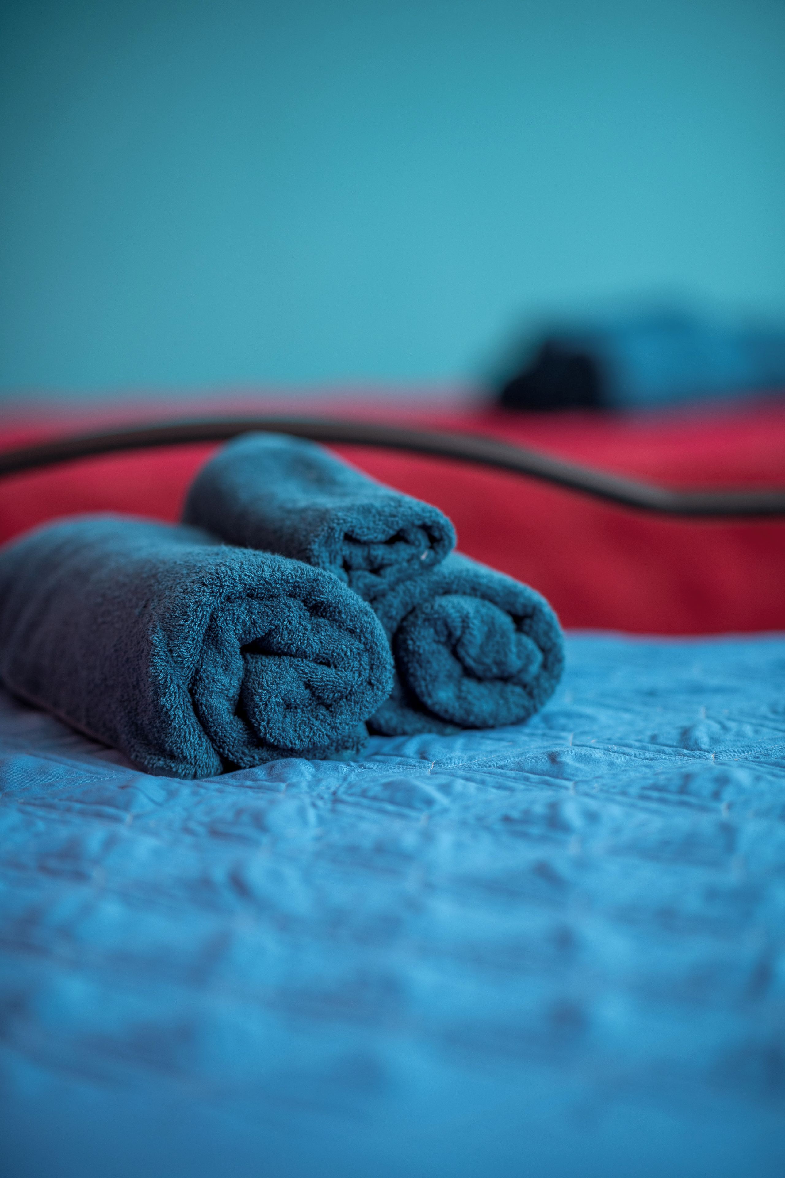 Un letto con una coperta blu e una coperta rossa.