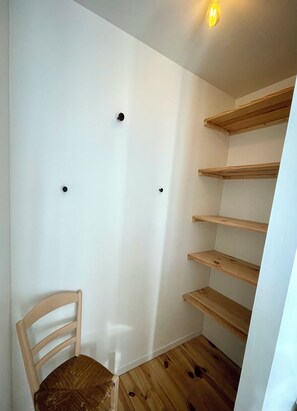 A room with a wooden chair, white walls, and wooden shelves. - L'Annexe : maison cosy avec jardin et vue mer (Ault)