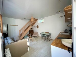 A compact living space with a kitchenette, a dining area, and a staircase. - L'Annexe : maison cosy avec jardin et vue mer (Ault)