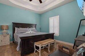 Een slaapkamer met een bed van donker hout, een witte bank, een lamp en een raam met zonwering.
