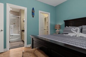 Un dormitorio con una cama grande, una mesita de noche, una lámpara y un cuadro colgado en la pared.