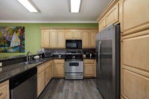 A kitchen with wooden cabinets, stainless steel appliances, and a microwave. - Fabulous Bayside Condo from Rent On Padre (South Padre Island)