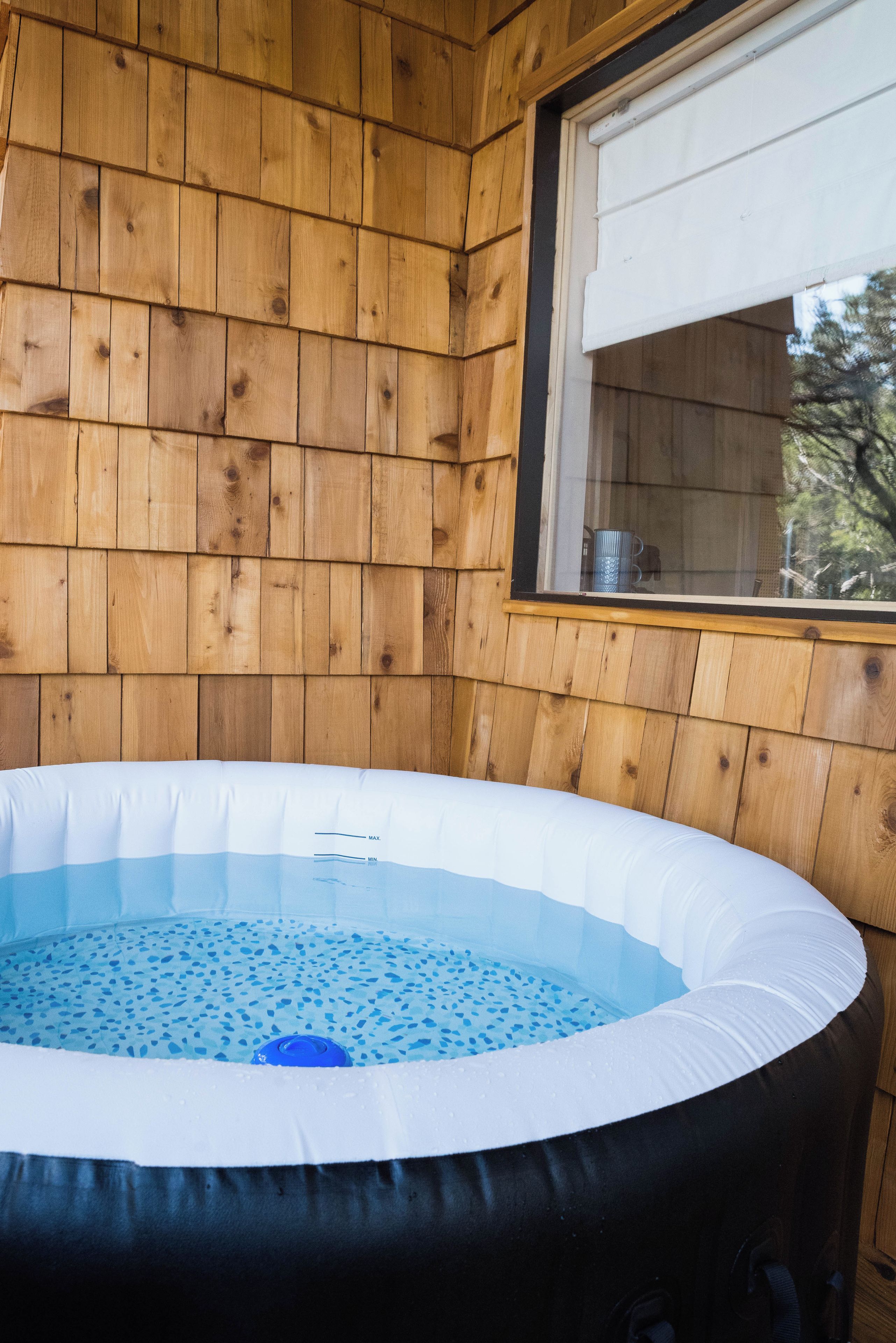 A hot tub in a wooden cabin with a window.