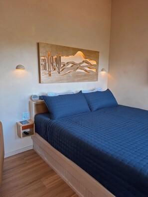 A bedroom with a bed, a nightstand, a wall-mounted artwork, and a bedside table. - The Canopy · Treetop Cabin, Hot Tub + Soaking Tub (Valley Mills)